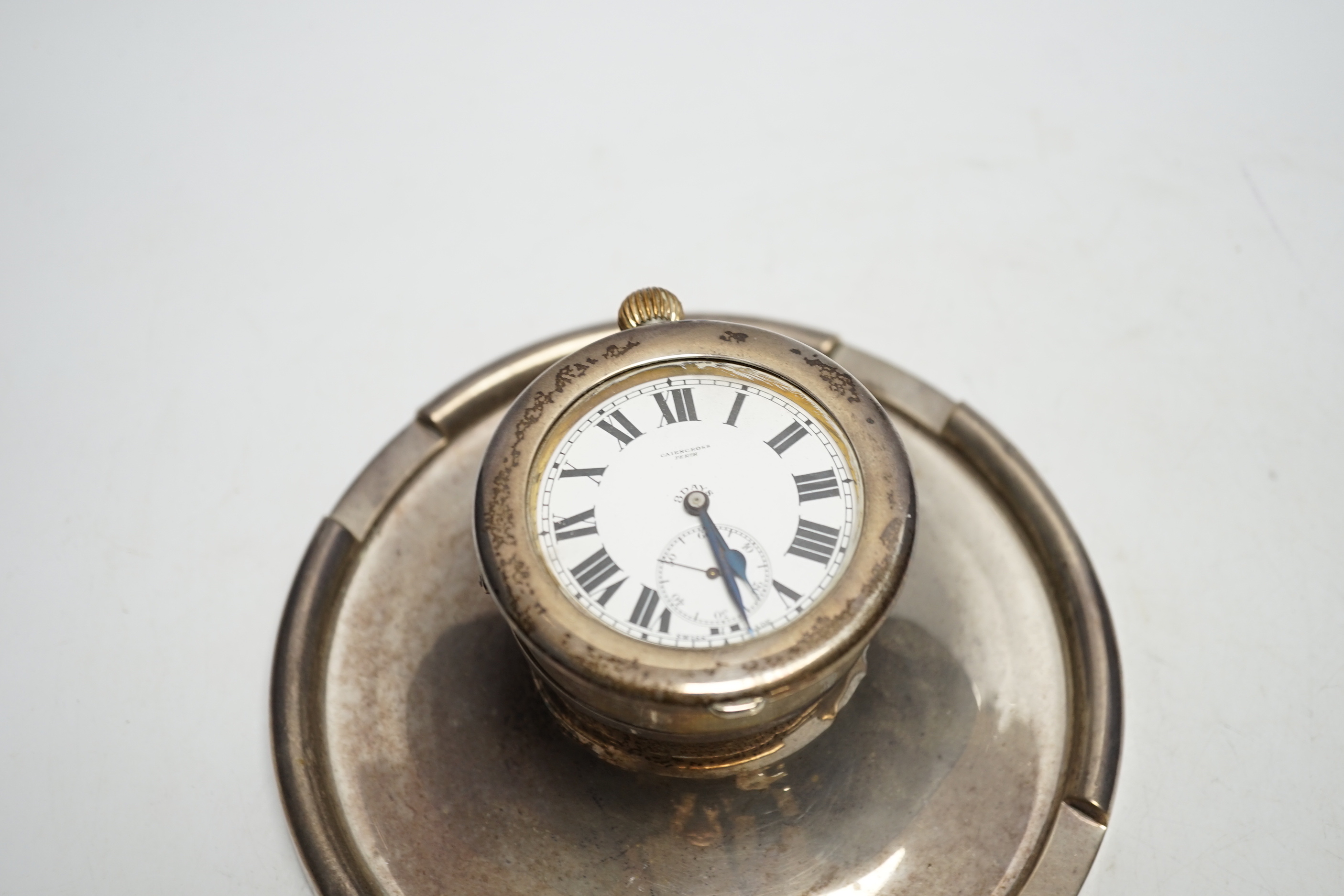 A George V silver mounted combination inkwell/pocket watch holder, Birmingham, 1926, containing an eight day pocket watch, Cairncross, Perth, base diameter 17.7cm.